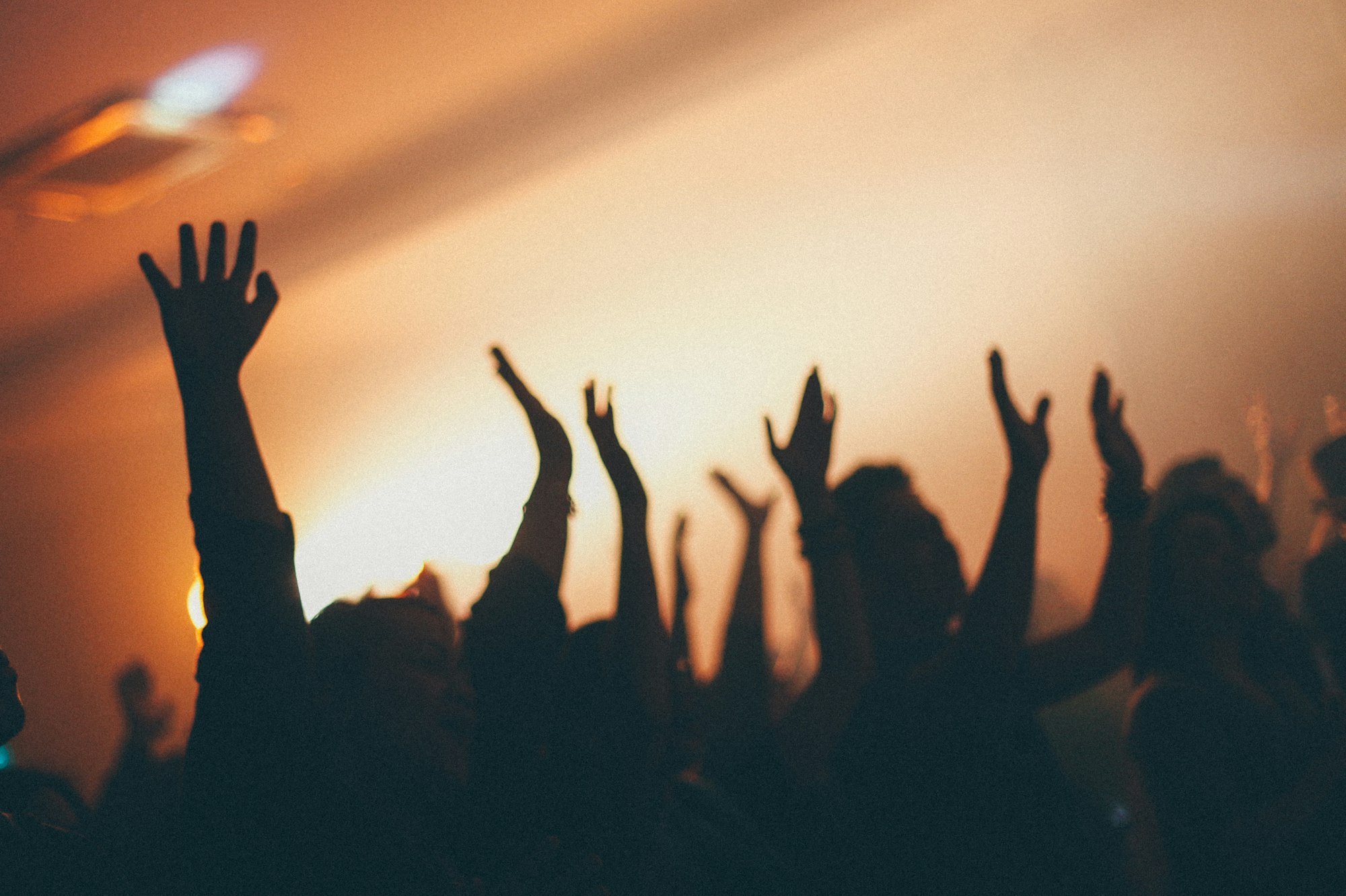 Silhouettes of raised hands in warm light